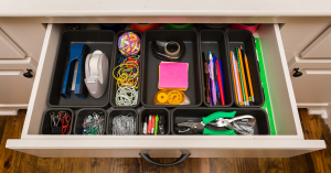 Organized desk drawer with office supplies neatly arranged in compartments.