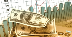 Stack of US dollar bills with financial charts and graphs in the background, representing investment and financial growth.