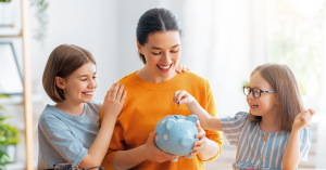 Mother and two daughters saving money with a piggy bank.