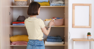 Woman organizing clothes in a tidy closet.