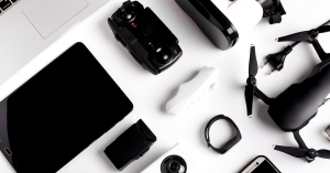A flat lay of various tech gadgets, including a drone, smartwatch, tablet, and VR headset, arranged on a white background.