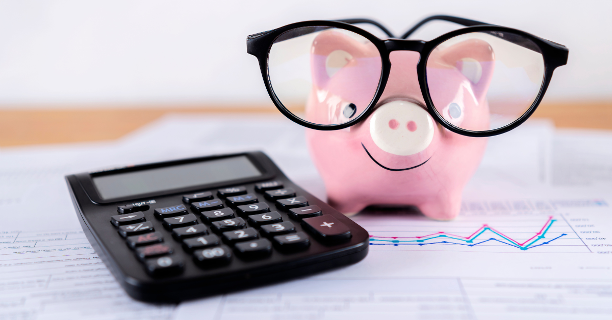 Piggy bank with glasses next to a calculator on top of financial documents.